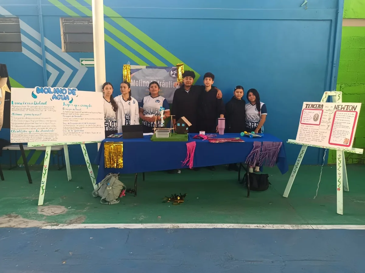 Estudiantes de Secundaria de Colegio Latino presentando un proyecto de ciencias sobre un molino de agua